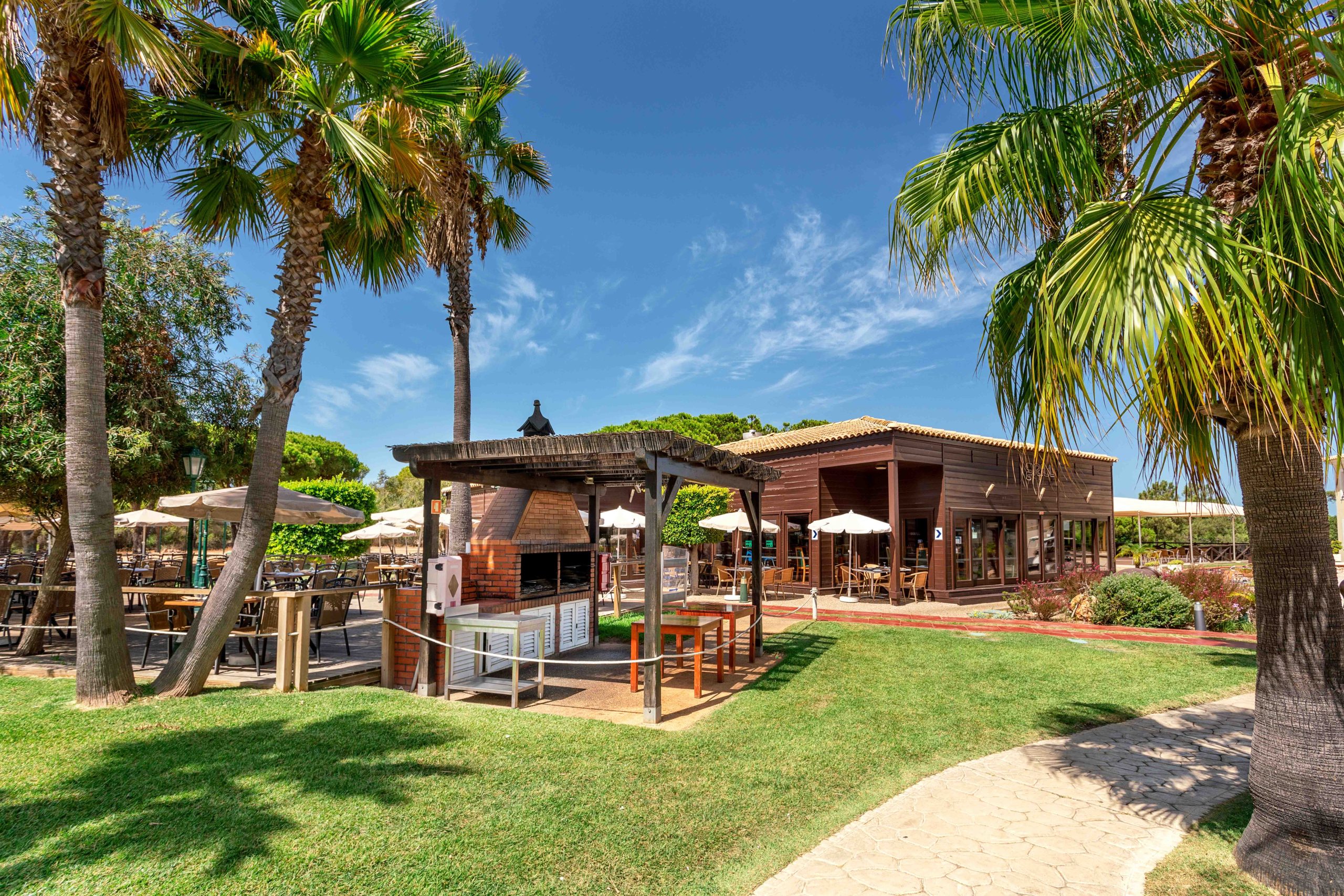 Restaurante Grill do hotel AP Adriana Beach Resort feito com base de madeira e localizado numa zona verde